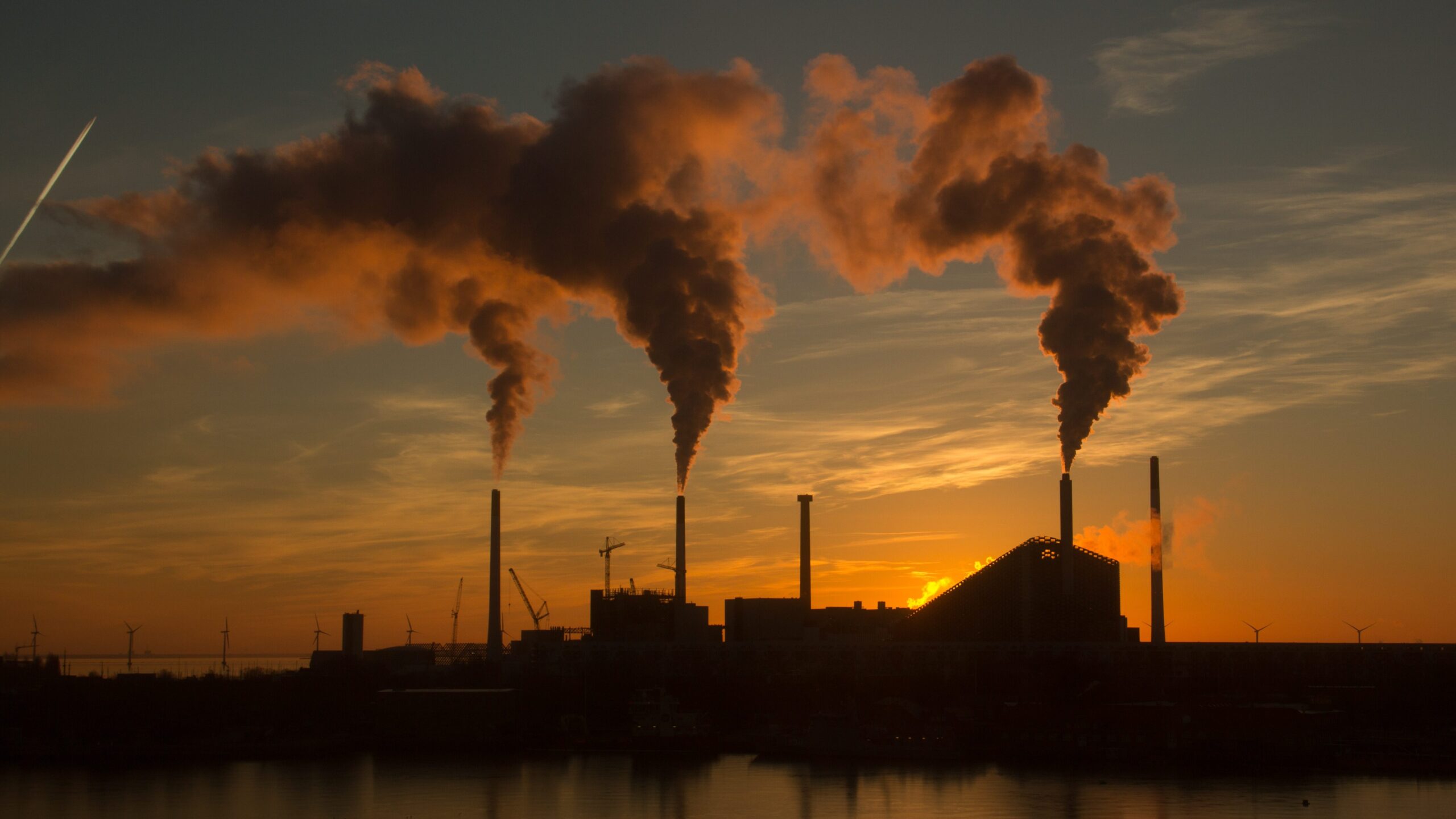 A low angle shot of a factory with emitting air pollution
